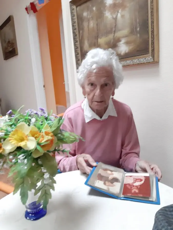 Grandma at a table with a vase of flowers, looking through a photo album